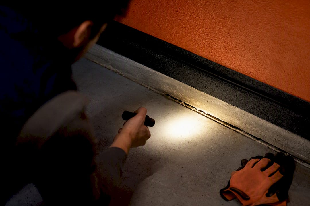 Flashlight inspecting a garage stem wall gap